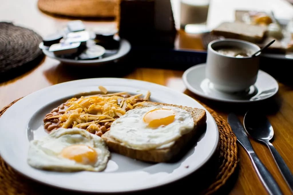 Desayuno clásico: Huevos al gusto, pan tostado de la casa, mantequilla, mermelada y bebida calient