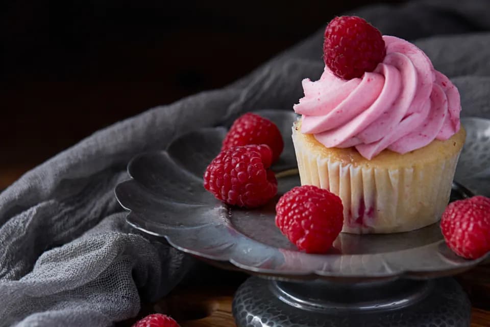 Cupcake de frutos rojos: Cupcake de vainilla con crema rosada de frambuesa y una frambuesa fresca encima.