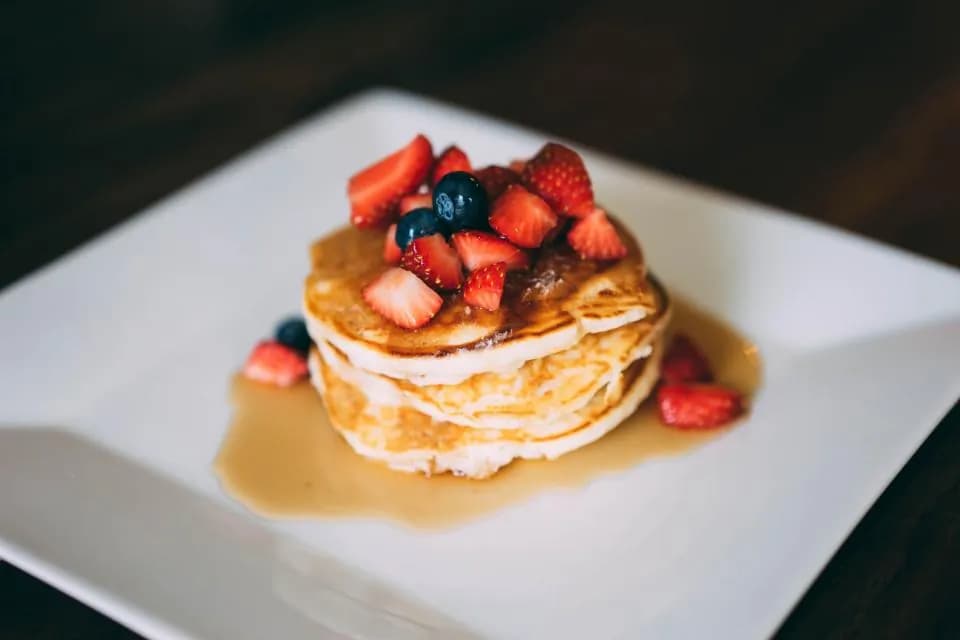 Pancakes con frutos rojos: Torre de pancakes esponjosos con fresas, arándanos, miel de maple y un toque de 