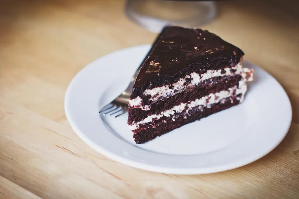 Torta de chocolate: Porción húmeda de bizcocho de chocolate con ganache intenso. La favorita de los 
