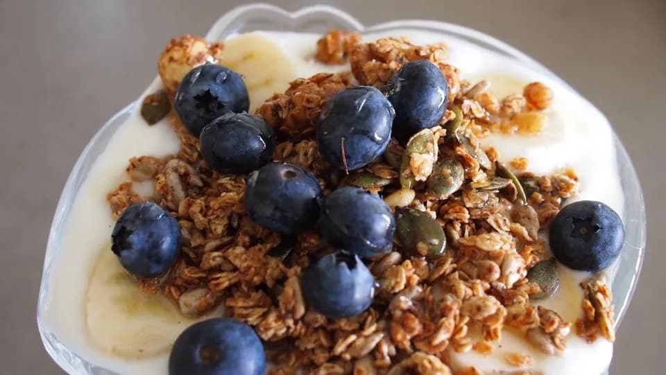 Bowl de yogur con granola: Yogur natural cremoso con granola crocante, fresas, arándanos y un hilo de miel.