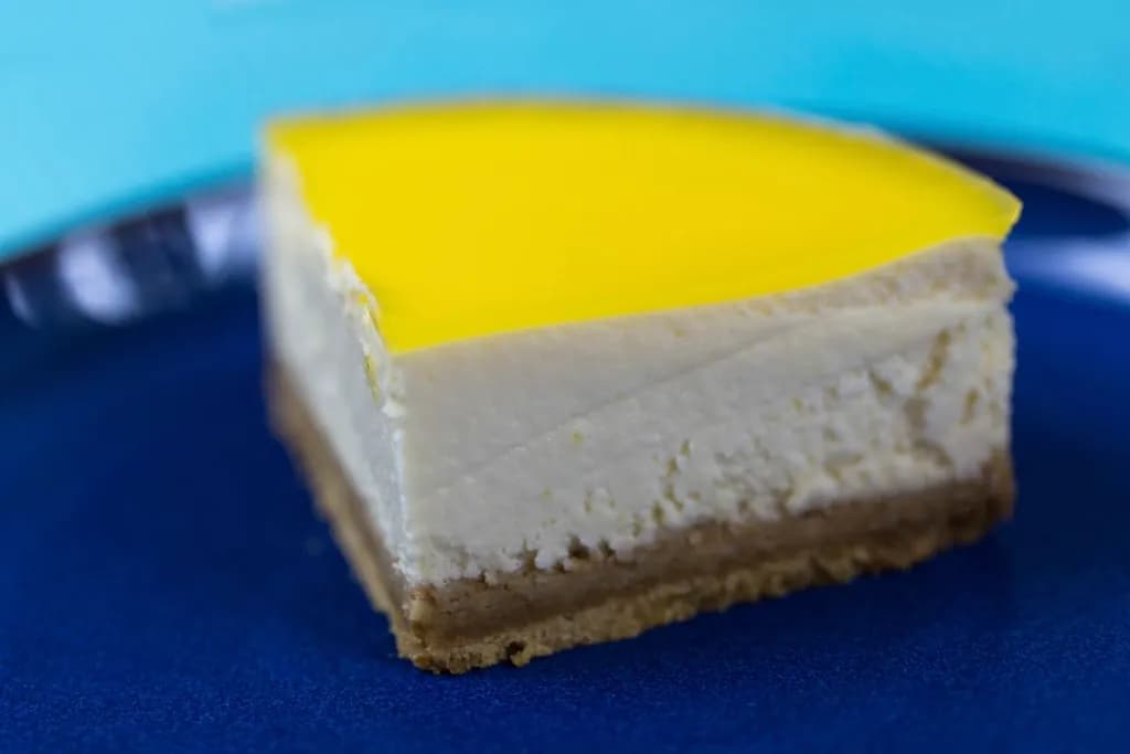 Cheesecake de maracuyá: Porción de cheesecake cremoso sobre base de galleta, con cobertura de maracuyá d